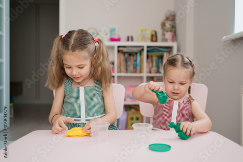 Little girls with lovely faces play with clay molding shapes, learning through playing with colored plasticine developing creativity