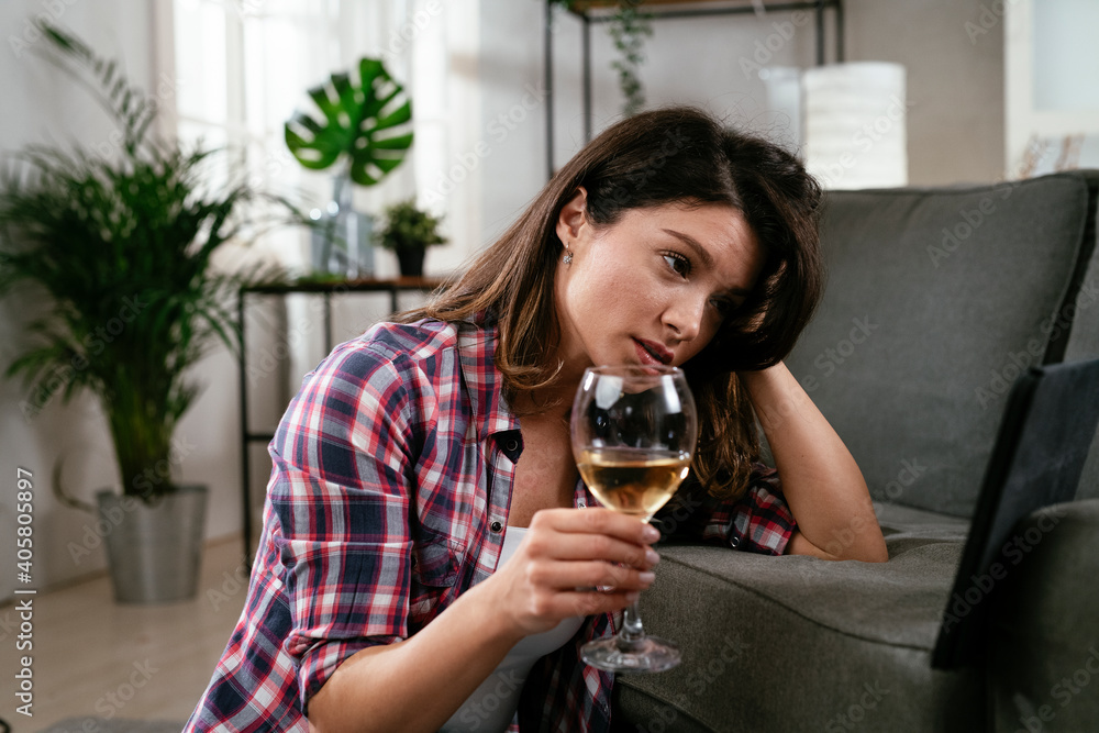 Sad woman drinking wine. Young woman having video call, talking and drinking wine at home Sad woman drinking wine. Young woman having video call, talking and drinking wine at home