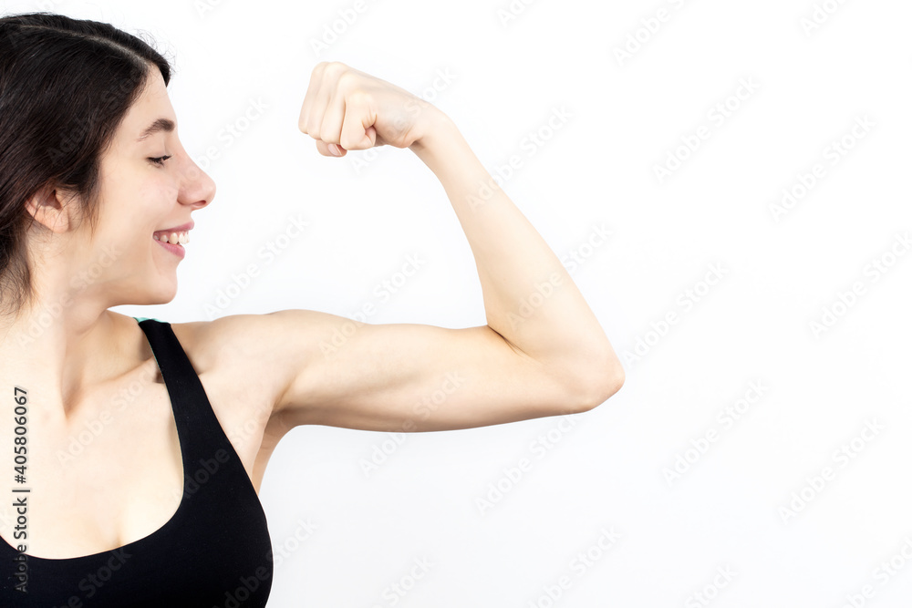 Young woman biceps in fitness wear isolated on white background.
Young woman biceps in fitness wear isolated on white background.