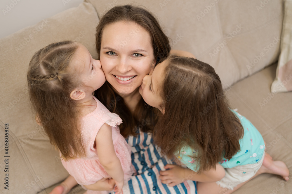 Lovely little daughters kissing sweet their sunny mother on checks. Happy family concept Lovely little daughters kissing sweet their sunny mother on checks. Happy family concept