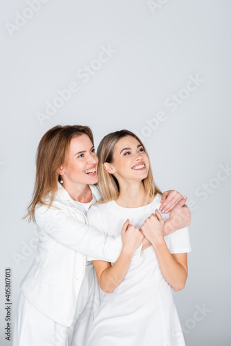 happy mother hugging young daughter isolated on grey, generation of women