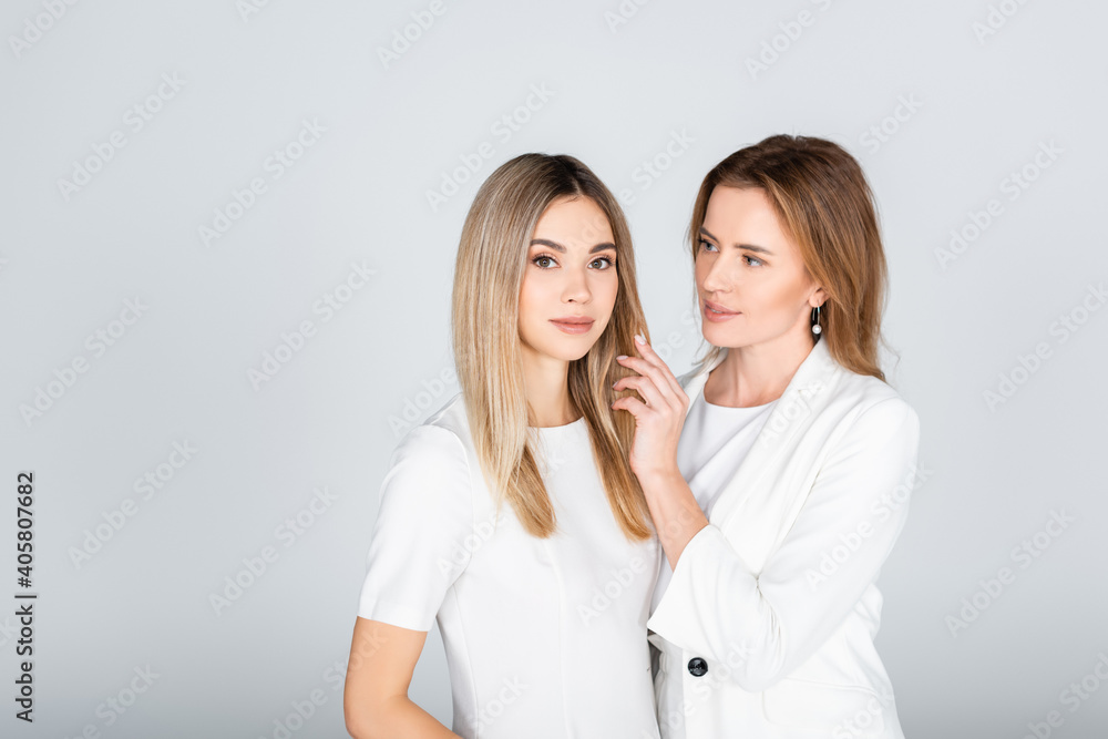 mother adjusting hair of young daughter isolated on grey mother adjusting hair of young daughter isolated on grey