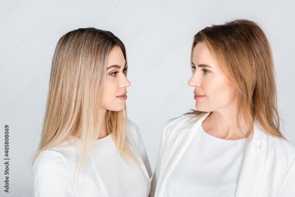mother and daughter looking at each other isolated on grey, generation of women mother and daughter looking at each other isolated on grey, generation of women