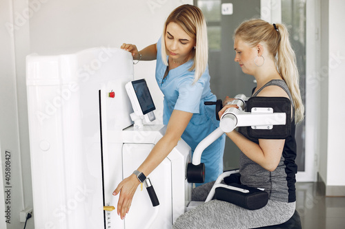 Young woman is doing exercises. Lady in the clinic. The patient uses the physical therapy equipment.