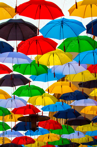 Different colored umbrellas hanging open above the street in the air.