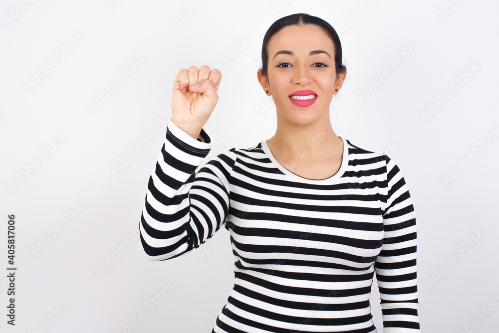 Young beautiful woman wearing stripped t-shirt against white background pointing up with fingers number ten in Chinese sign language Shi Young beautiful woman wearing stripped t-shirt against white background pointing up with fingers number ten in Chinese sign language Shi
