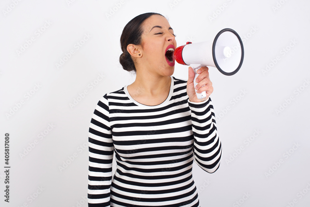 Young beautiful woman wearing stripped t-shirt against white background Through Megaphone with Available Copy Space Young beautiful woman wearing stripped t-shirt against white background Through Megaphone with Available Copy Space