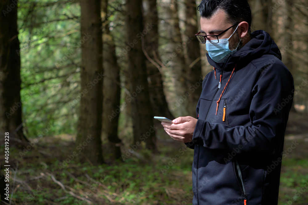 young man walks through the woods during the new normal using technology to communicate young man walks through the woods during the new normal using technology to communicate