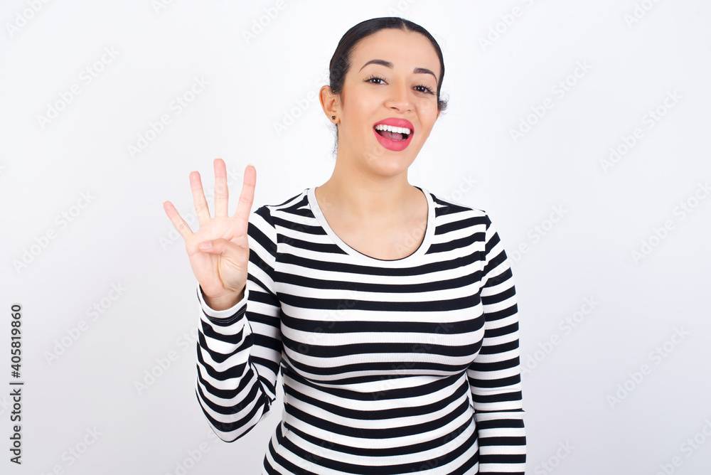 Young beautiful woman wearing stripped t-shirt against white background showing and pointing up with fingers number four while smiling confident and happy. Young beautiful woman wearing stripped t-shirt against white background showing and pointing up with fingers number four while smiling confident and happy.