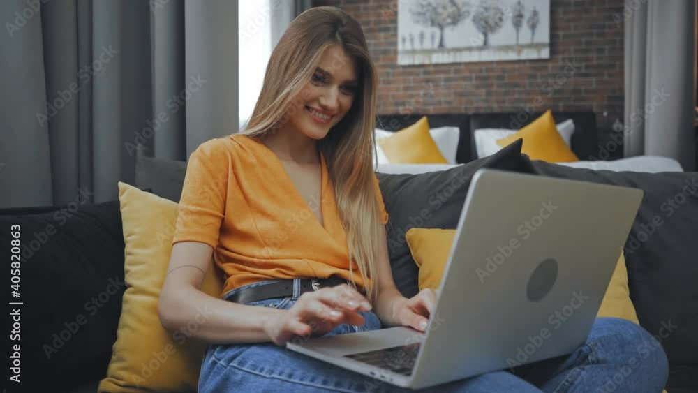 freelancer using laptop while sitting on sofa in hotel room freelancer using laptop while sitting on sofa in hotel room