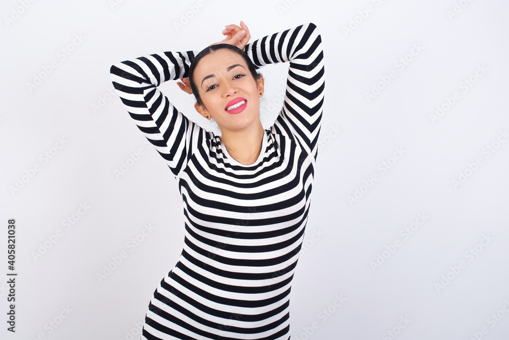 Young beautiful woman wearing stripped t-shirt against white background stretching arms, relaxed position. Young beautiful woman wearing stripped t-shirt against white background stretching arms, relaxed position.