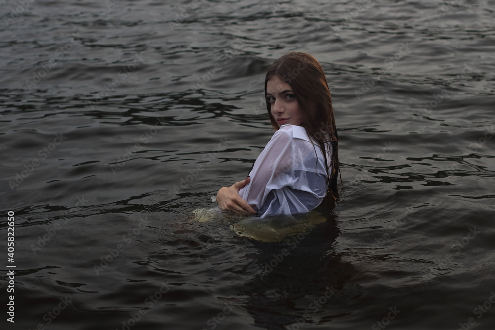 Fototapeta premium Young woman in the black water dressed white shirt