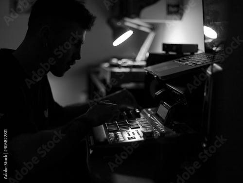 Beatmaker producing some beats with a drum machine in his home studio