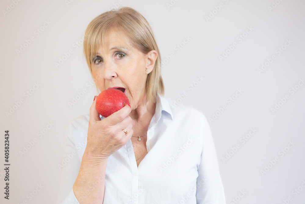 Portrait of senior woman holding an apple by her mouth Portrait of senior woman holding an apple by her mouth