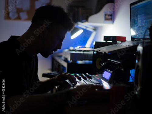 Beatmaker producing some beats with a drum machine in his home studio