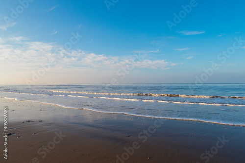 relaxing and gentle calming waves flowing into a beach at sundown, with a vivid blue sky and reflection. calming fresh air walks into nature during corona virus lockdowns