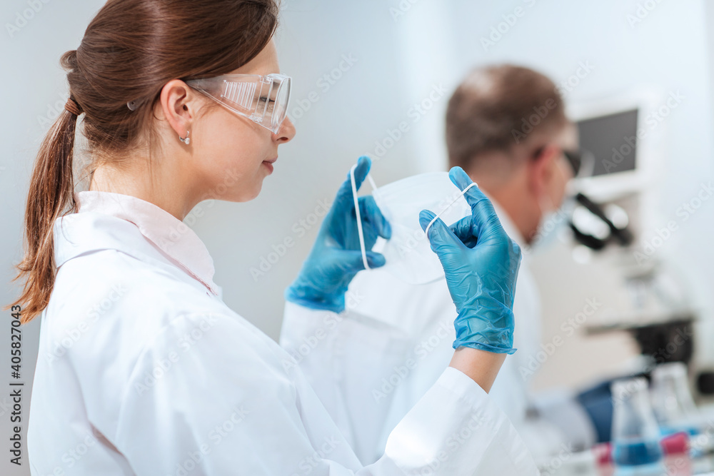 female scientist putting on a protective mask in the lab. female scientist putting on a protective mask in the lab.