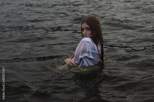 Sexy woman in the water.Dressed wet white shirt