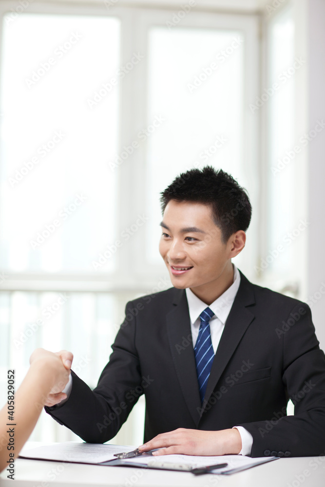 Portrait of young businessman executives extending hands to shake Portrait of young businessman executives extending hands to shake
