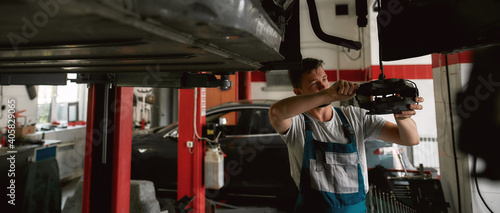 Young caucasian mechanic checking car while standing under bottom © Svitlana