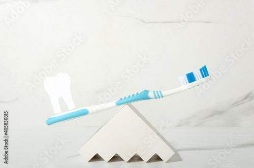 Closeup of blue toothbrush and decorative tooth as a healthcare balance