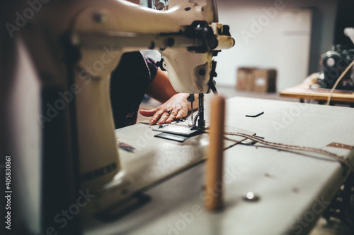 Manos trabajando en fábrica. Trabajador cosiendo trenzas de yute para calzado.