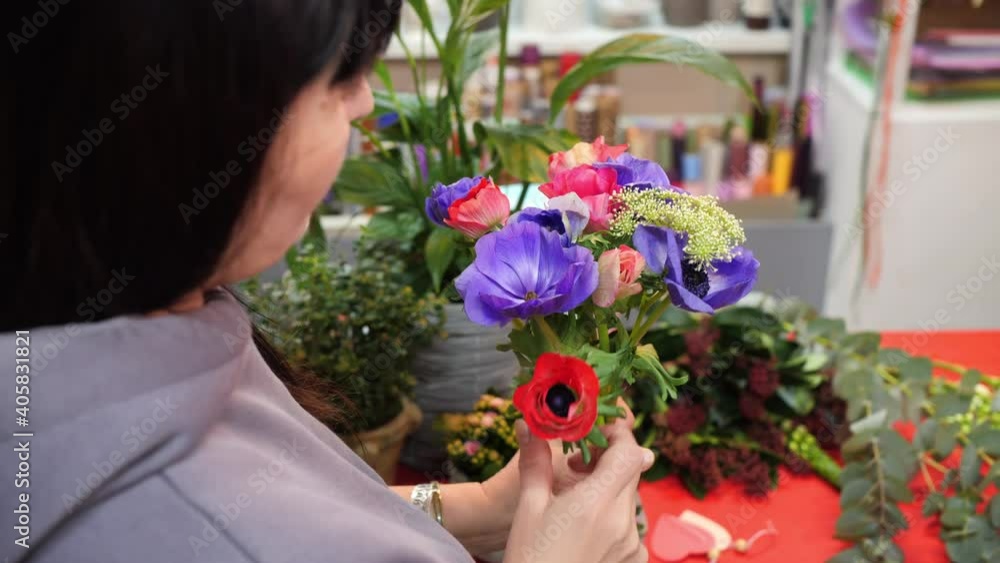 Female florist holding flowers bunch in hands for bouquet view from shoulder. Creative florist making flowers composition in workshop Female florist holding flowers bunch in hands for bouquet view from shoulder. Creative florist making flowers composition in workshop