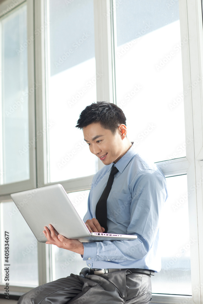 Portrait of young businessman using laptop in corridor Portrait of young businessman using laptop in corridor