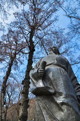 Принти на полотні stone chinese statue against bare trees and blue sky