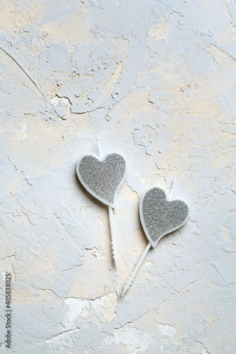 Valentine concept, silver shining heart-shaped candles with glitter on grey texture