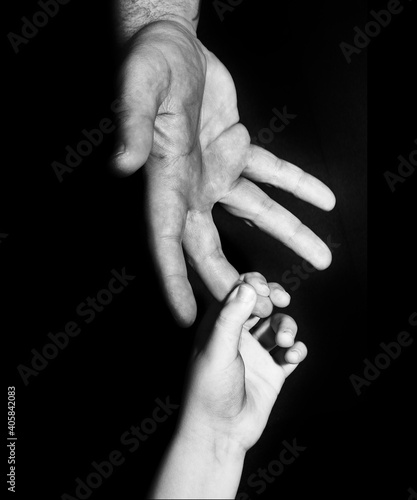 a boy holding on to his fathers finger in black and white