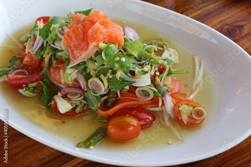 Asian spicy raw salmon salad with herbs and vegetables.