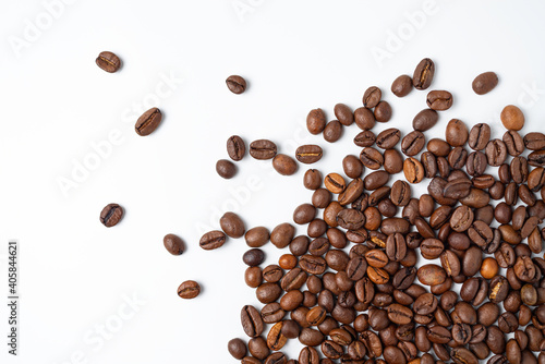 Coffee beans lie on a white surface and protrude into the picture - white background with coffee beans on it.