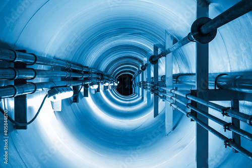 Confined space inside underground tunnel. Construction from engineering technology for infrastructure i.e. power line or cable, steel pipe in perspective view. To transport water, gas and electricity. photo