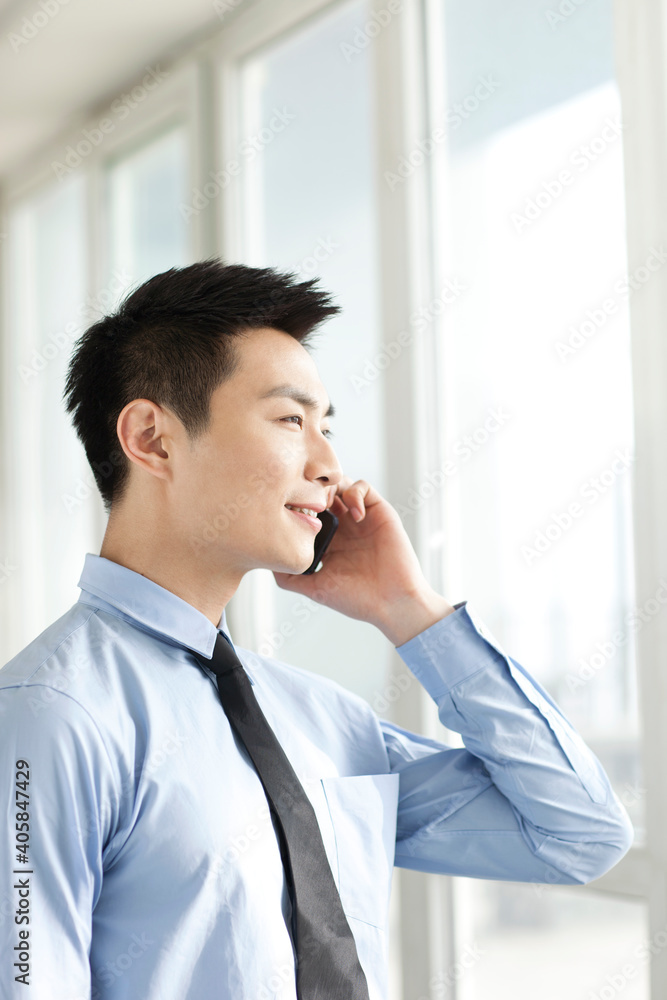 Portrait of young businessman talking on cell phone in office Portrait of young businessman talking on cell phone in office