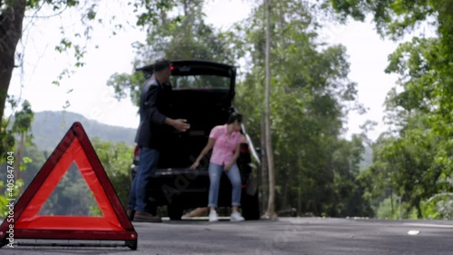 Wallpaper Mural Close up red emergency stop sign standing on road. Worried and angry couple walking near his broken car talking on phone with insurance agent. Close up triangle on side road Torontodigital.ca