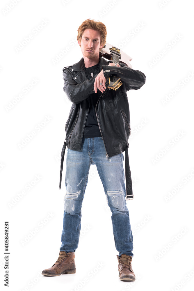 Macho confident young rocker in leather jacket with electric guitar carrying on shoulder looking at camera. Full body isolated on white background. Macho confident young rocker in leather jacket with electric guitar carrying on shoulder looking at camera. Full body isolated on white background.