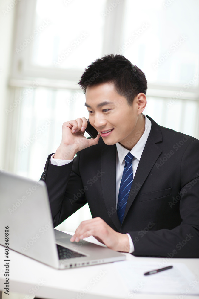 Portrait of businessman sitting at desk and using cell phone Portrait of businessman sitting at desk and using cell phone