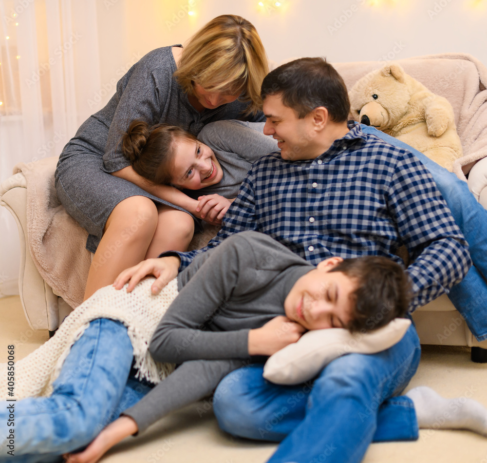 portrait of a family sitting on a sofa at home, four people having fun together