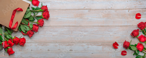 Fotografie Red roses in craft shopping bag, a wooden surface