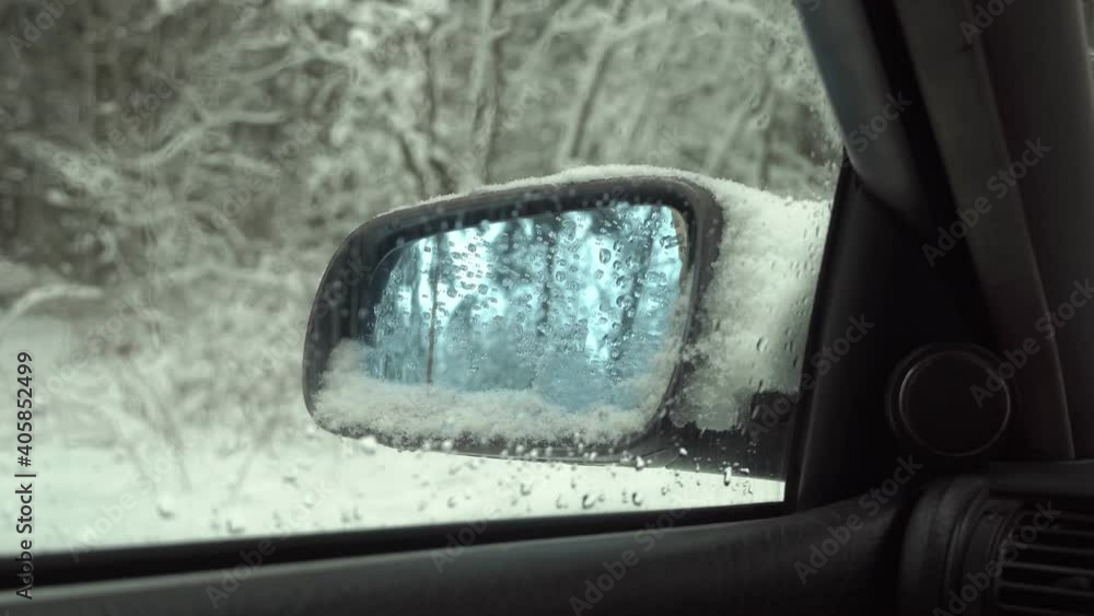 The car is standing on a snowy snowy mountain road in the forest in the winter snow. The point of view of the driver looking in the side mirror. Side mirror, heating. The car is standing on a snowy snowy mountain road in the forest in the winter snow. The point of view of the driver looking in the side mirror. Side mirror, heating.