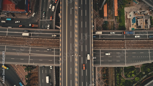 Top down cross traffic highway with cars, trucks aerial. Urban transportation at bridge road at metropolis city of Manila, Philippines, Asia. Cinematic cityscape of downtown freeway drone shot