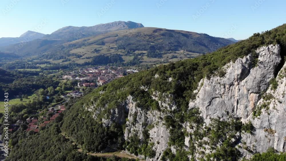 Aerial view with a drone of the entrance of the green mountains of northern Spain with a town of Aerial view with a drone of the entrance of the green mountains of northern Spain with a town of