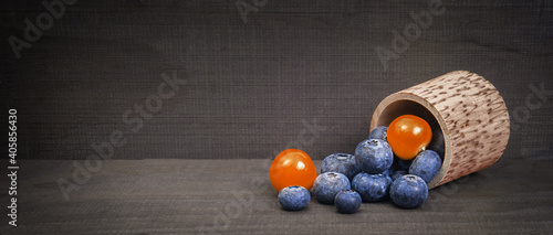 blueberry berries in a wooden barrel with physalis berries on a wooden background