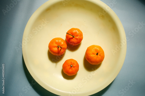 Flat lay small ripe tangerines on yellow plate