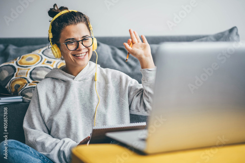 Millennial woman having video call on her computer at home. Smiling girl studying online with teacher. photo