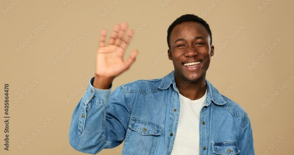 Man waving hand and greeting hello over beige background Man waving hand and greeting hello over beige background