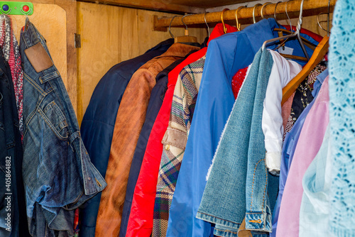 Old and new clothes in the closet on hangers and drawers. Second hand reuse. Decluttering and cleaning the cabinet