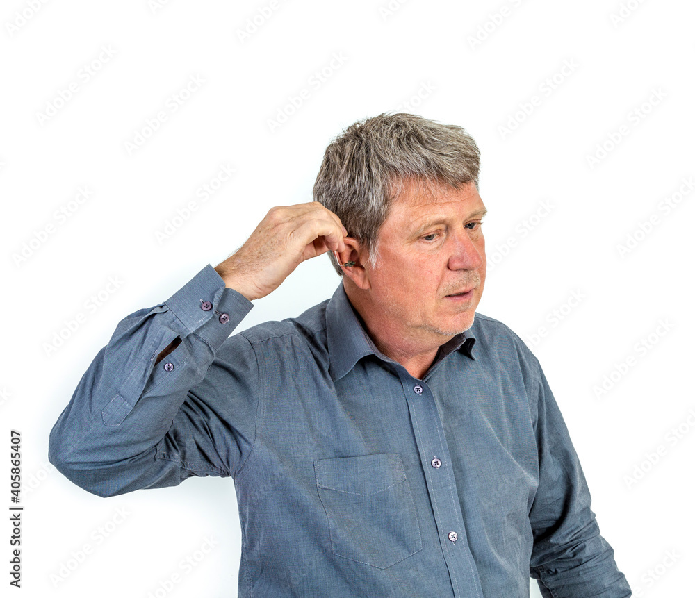 man puts hearing aid in the ear man puts hearing aid in the ear