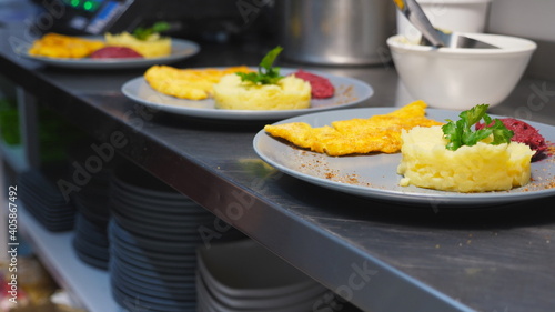 Male hand adding sprigs of parsley onto mashed potatoes on plates. Arm of chef serving puree with crispy breaded chicken fillets at restaurant. Concept of preparing food. Close up Slow motion